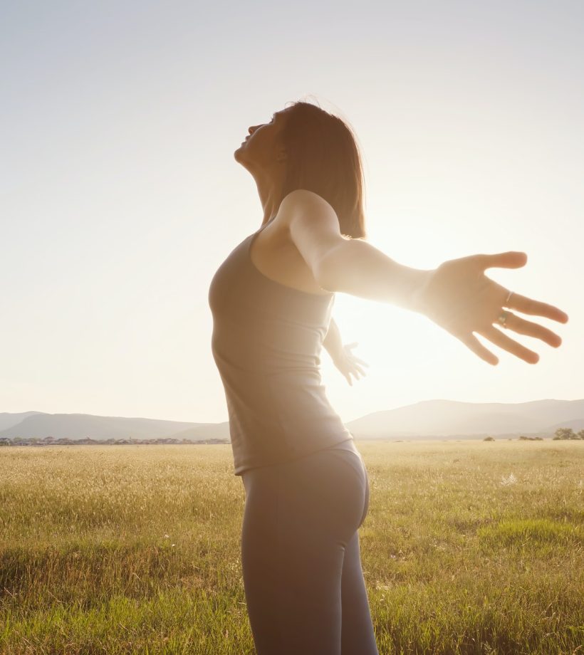 Young girl spreading hands with joy and inspiration facing the sun